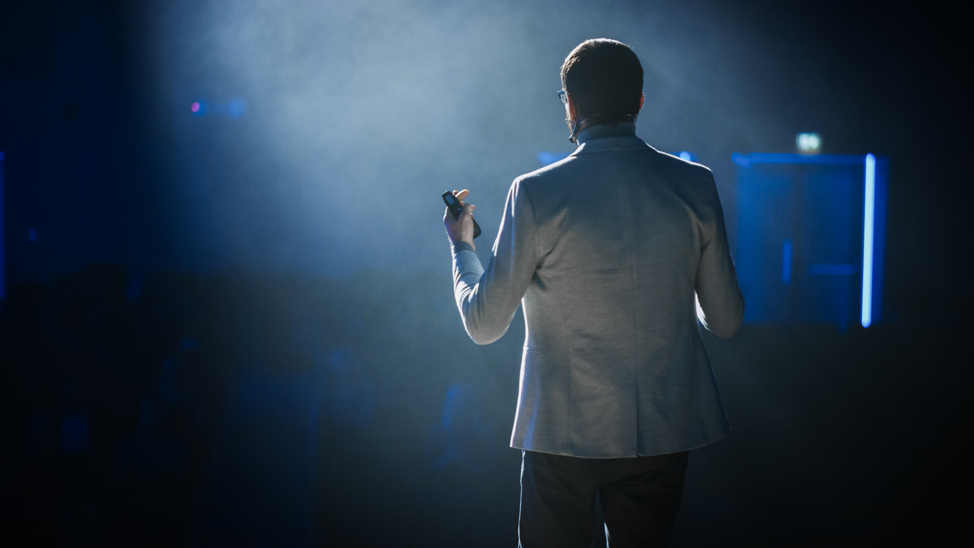 man on stage presenting to audience